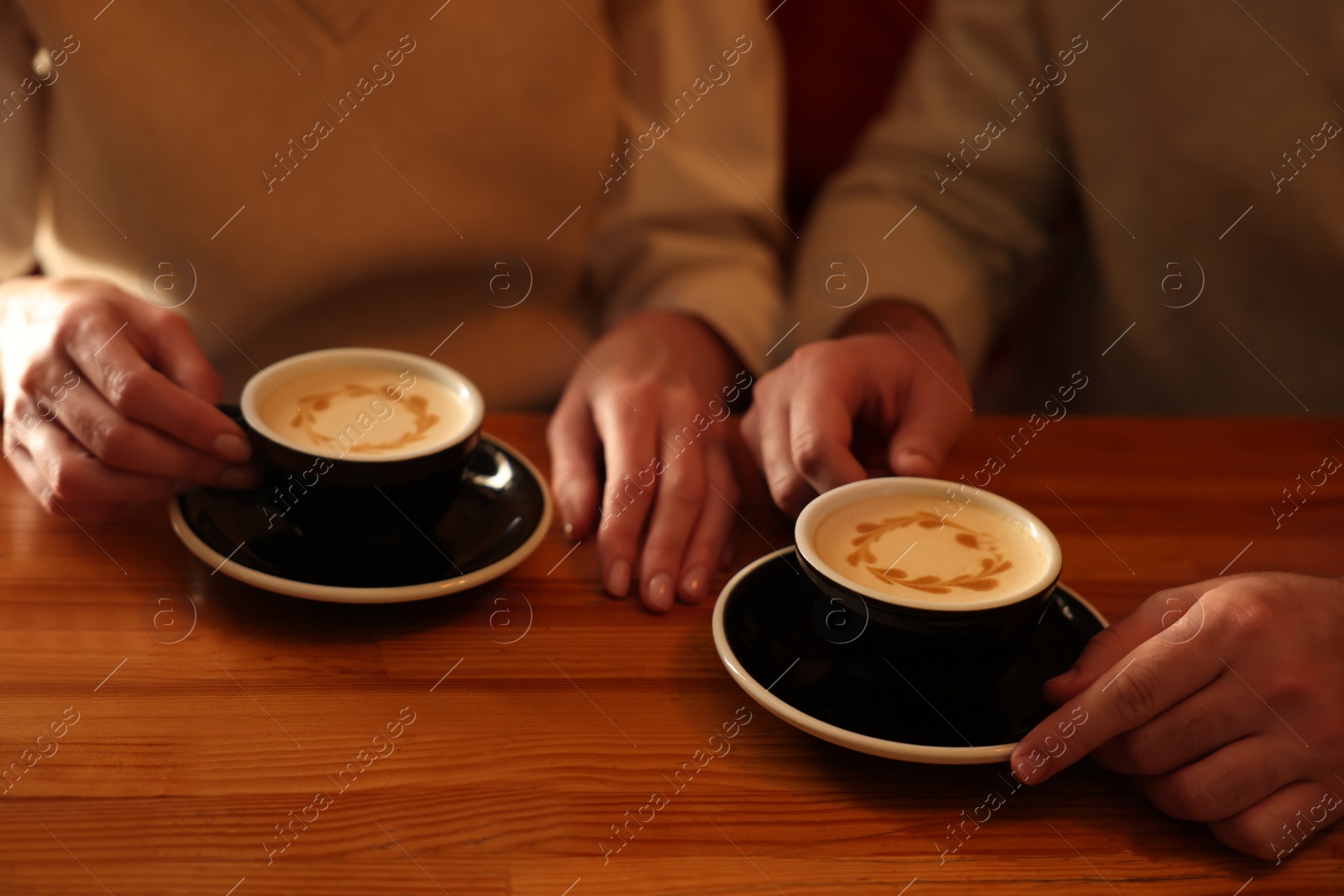 Photo of Couple with cups of aromatic coffee at wooden table, closeup