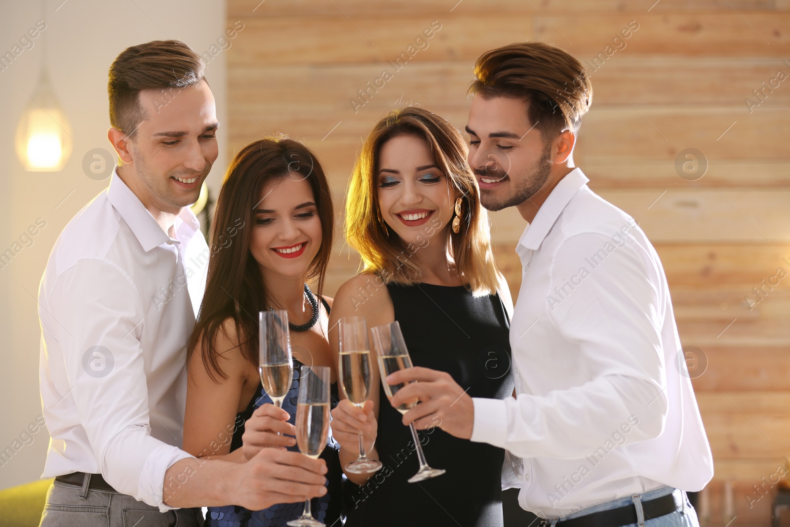 Photo of Friends clinking glasses with champagne at party indoors