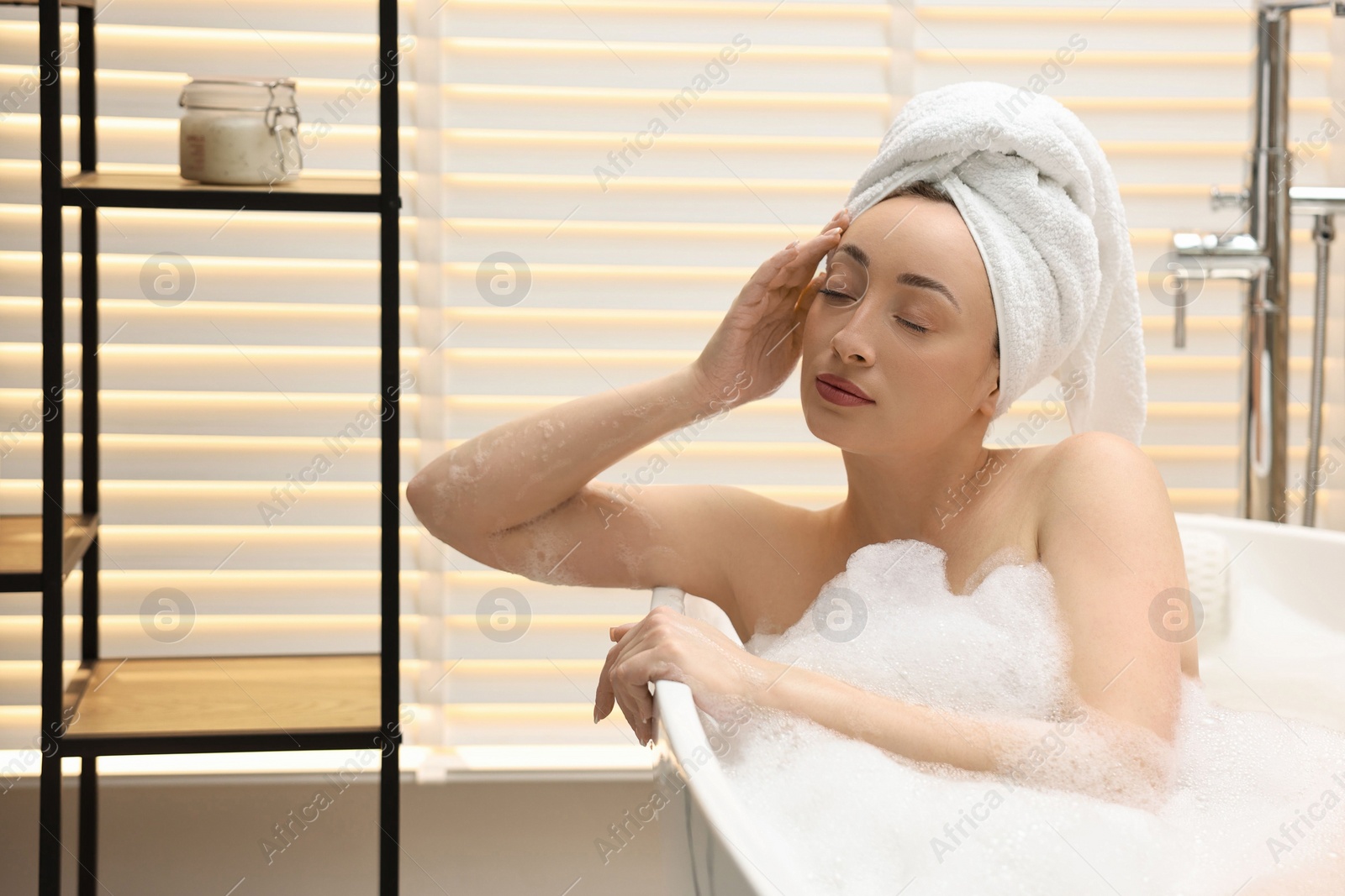 Photo of Beautiful woman taking bath with foam in tub indoors