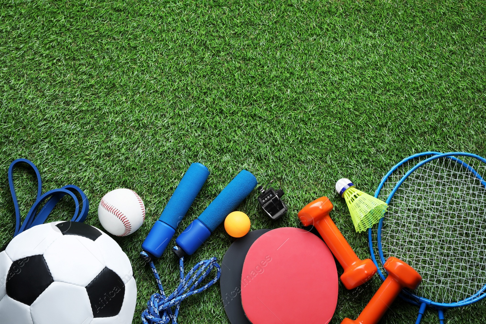 Photo of Set of different colorful sports equipment on green grass, flat lay. Space for text