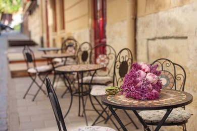 Photo of Bouquet of beautiful flowers on table in outdoor cafe