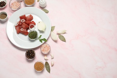 Raw beef meat and different ingredients for cooking delicious goulash on pink marble table, above view. Space for text