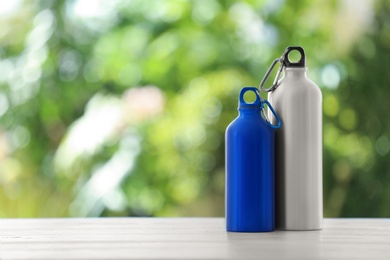 Photo of Sports water bottles on table against blurred background. Space for text