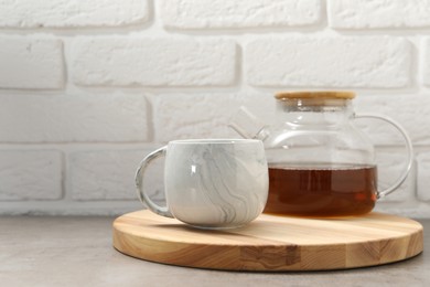 Aromatic tea in glass teapot and cup on gray table against white brick wall, space for text