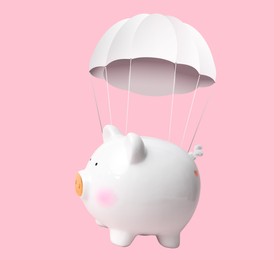 Image of White piggy bank with parachute flying on pink background