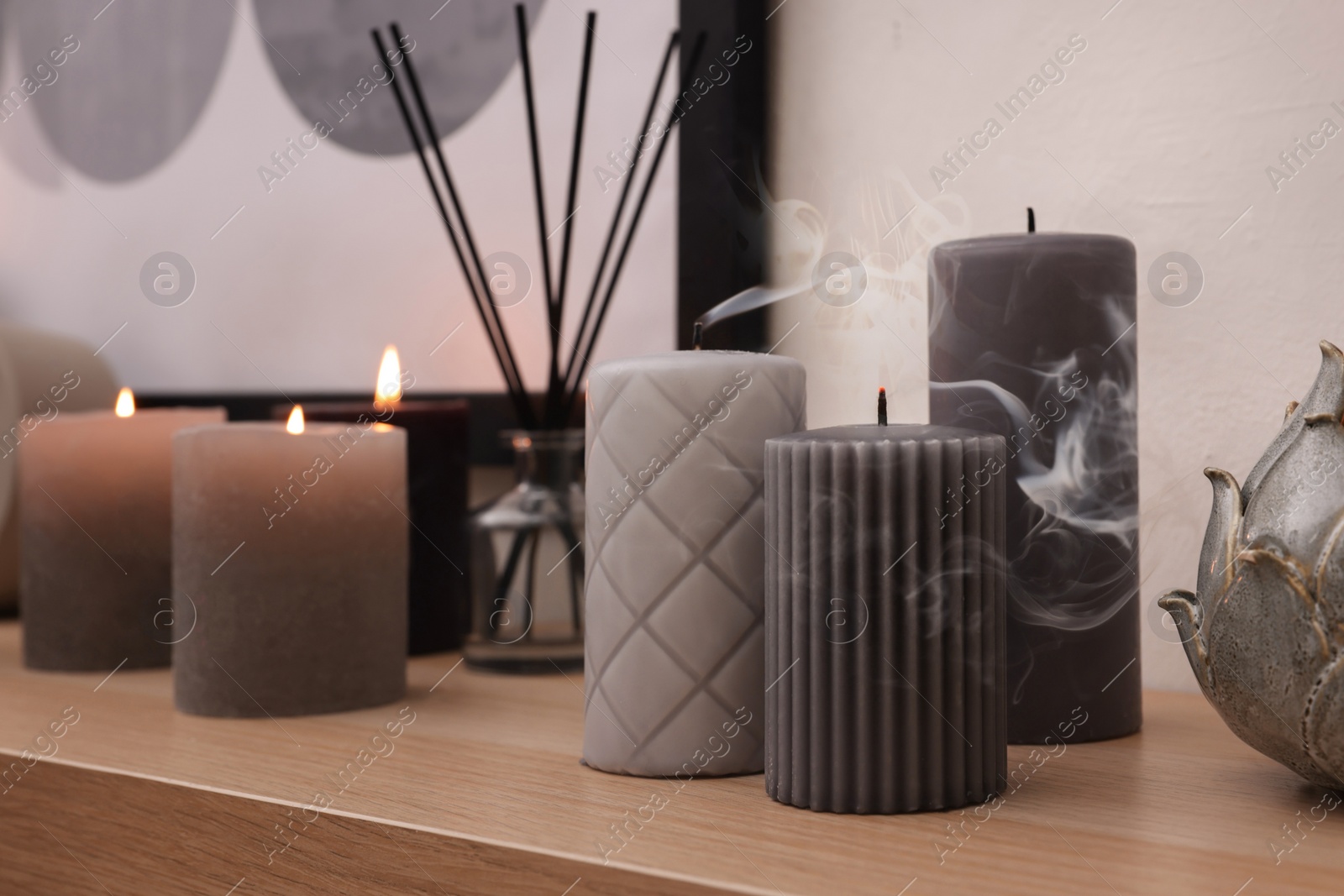 Photo of Blown out candles and air freshener on wooden shelf indoors