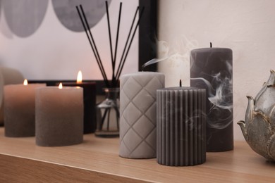 Photo of Blown out candles and air freshener on wooden shelf indoors