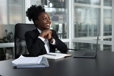 Photo of Happy woman working at table in office. Lawyer, businesswoman, accountant or manager