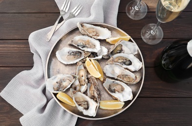 Fresh oysters with cut juicy lemon served on table, flat lay