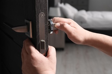 Photo of Handyman repairing door handle indoors, closeup view