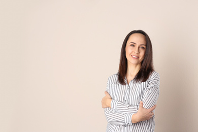 Portrait of beautiful mature woman on beige background. Space for text