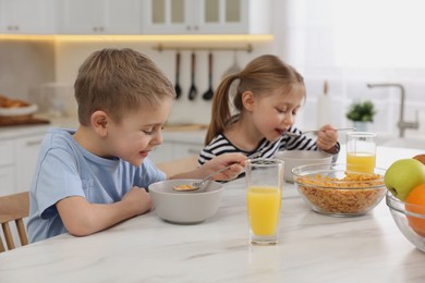 Photo of Little children having breakfast at table in kitchen, selective focus