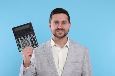 Happy accountant with calculator on light blue background