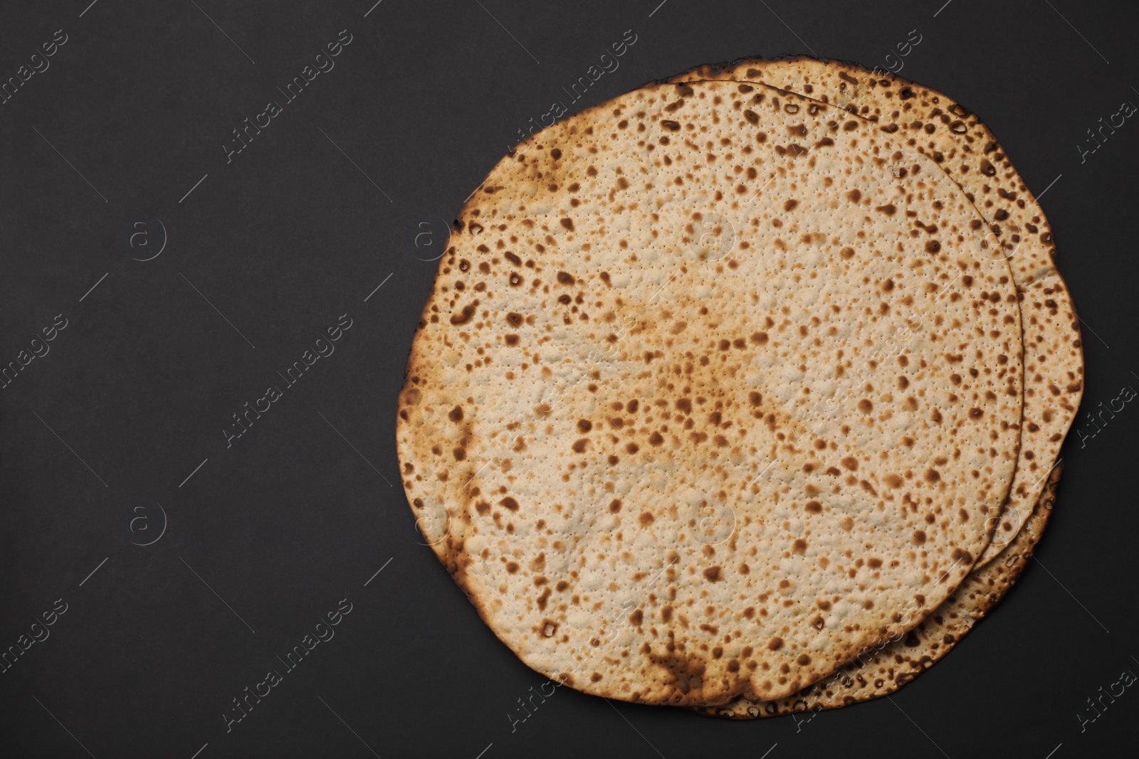 Photo of Tasty matzos on black background, top view with space for text. Passover (Pesach) celebration