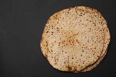Photo of Tasty matzos on black background, top view with space for text. Passover (Pesach) celebration