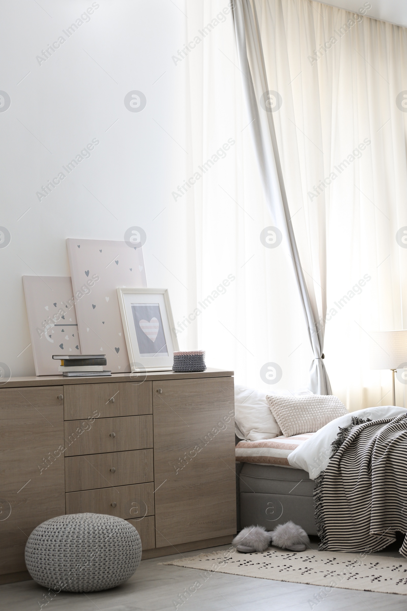 Photo of Modern chest of drawers in beautiful bedroom. Interior design