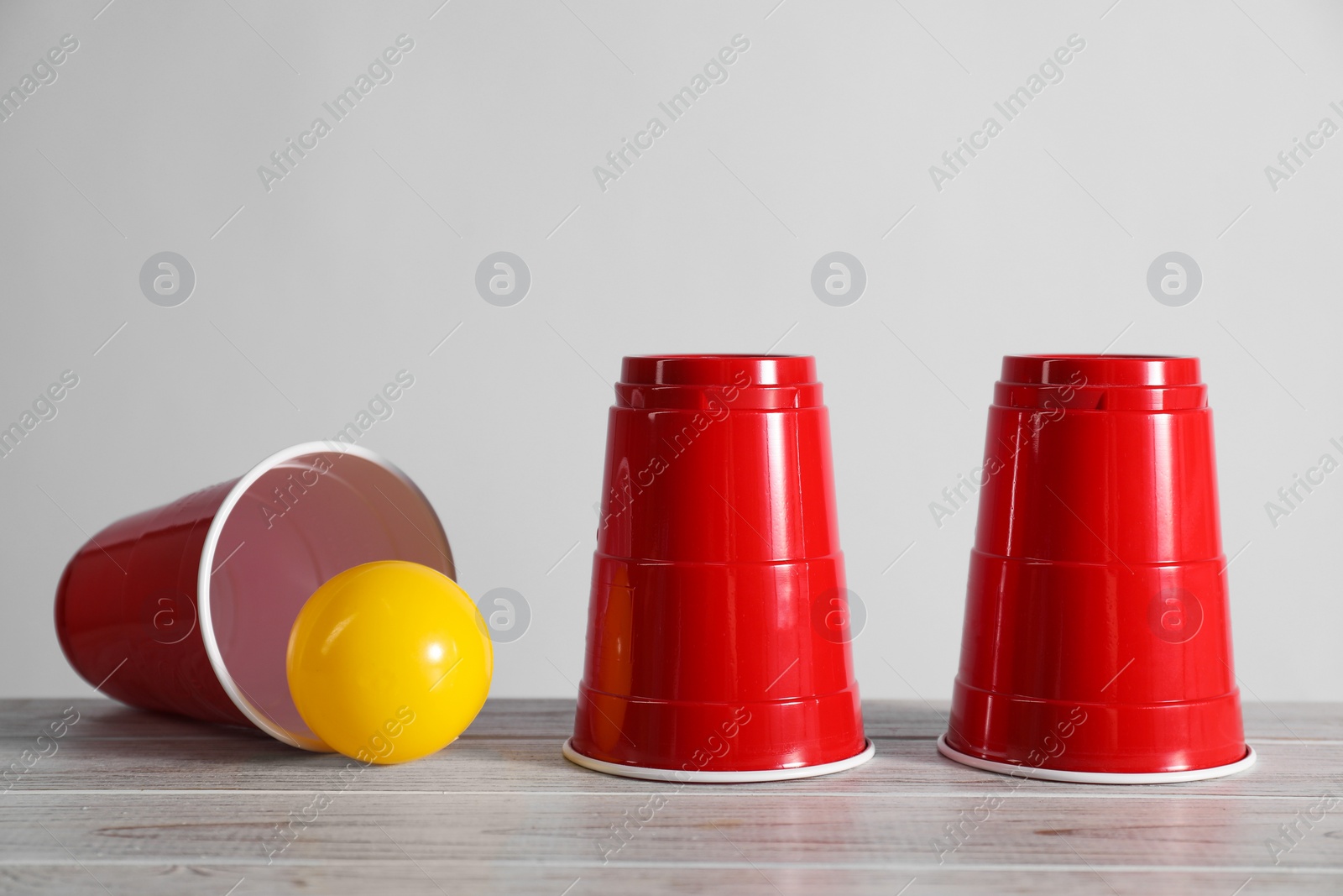 Photo of Shell game. Three red cups and ball on wooden table