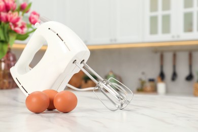 Modern mixer and eggs on white marble table in kitchen, space for text