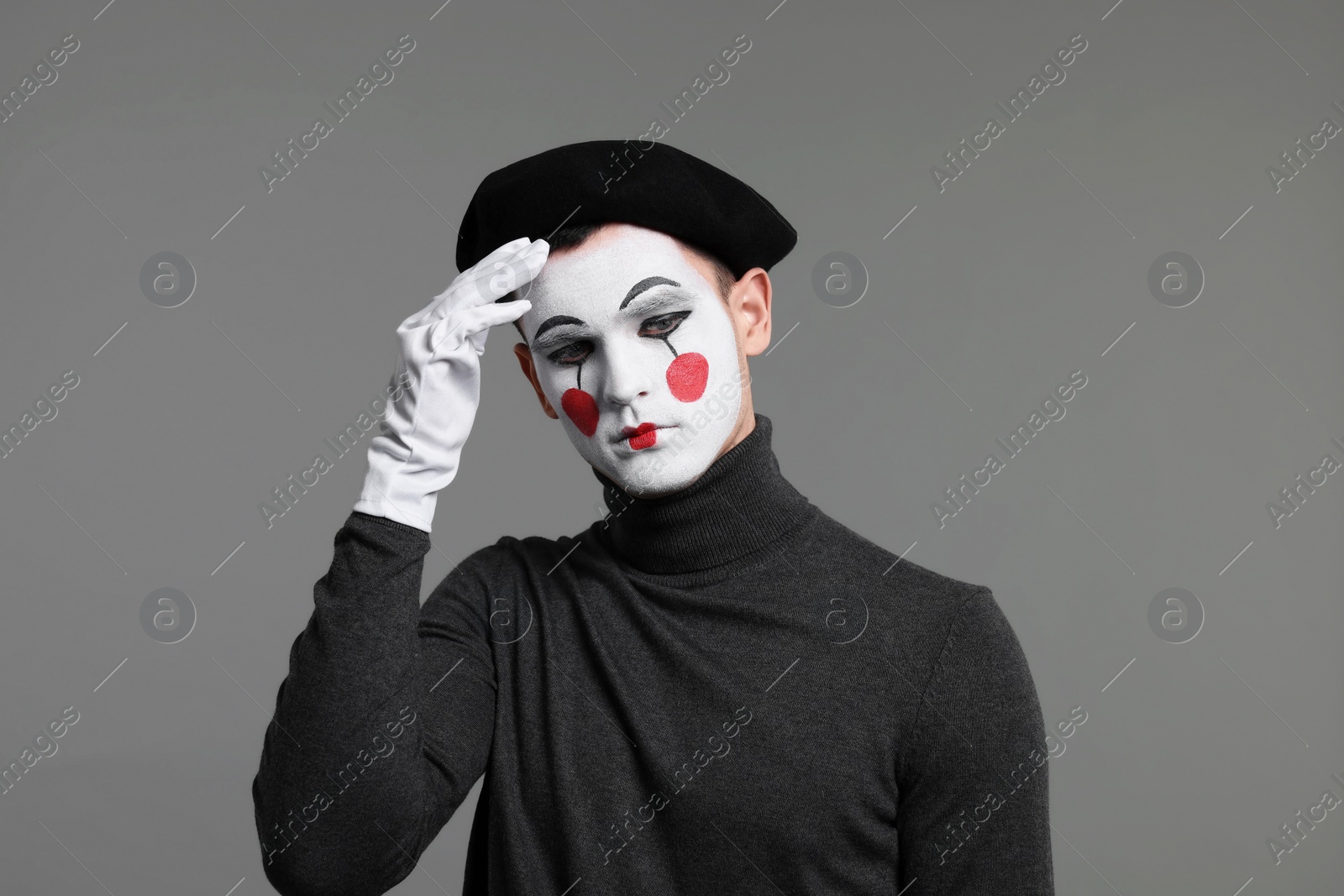 Photo of Mime artist in beret posing on grey background