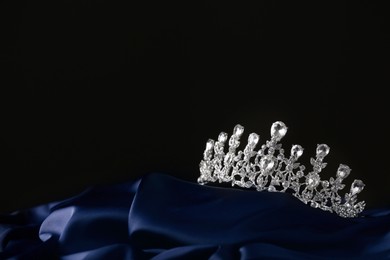 Beautiful silver tiara with diamonds on dark cloth. Space for text