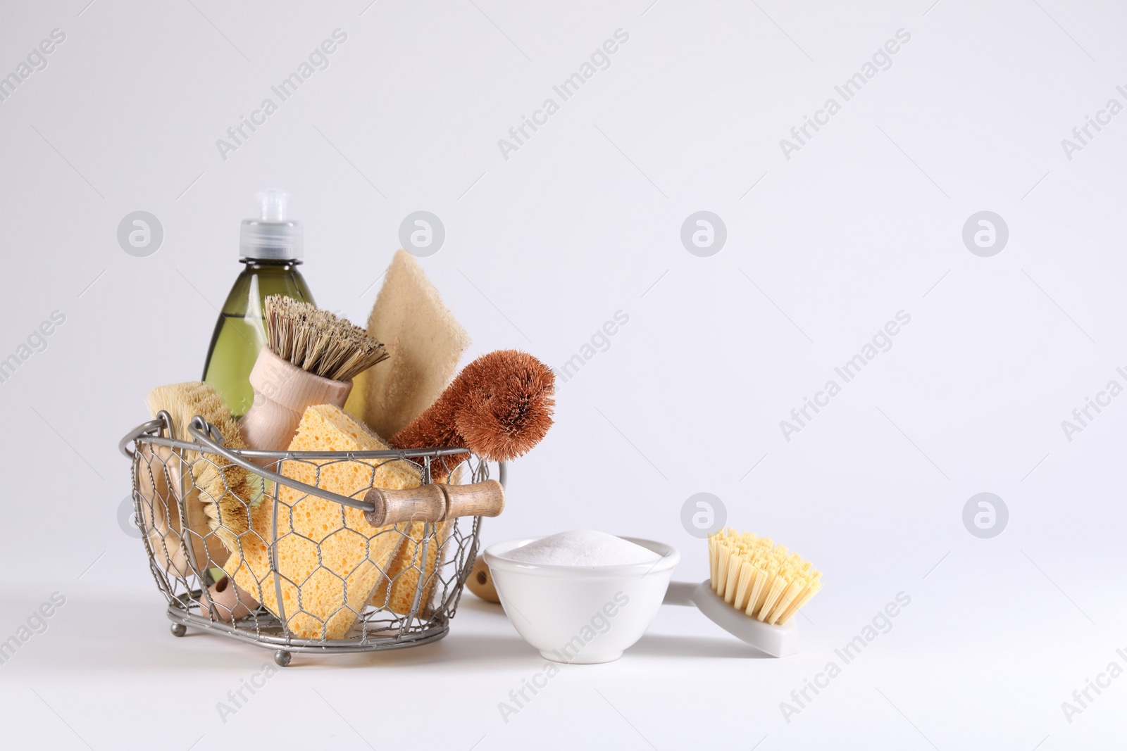 Photo of Set of different cleaning supplies in basket on white background