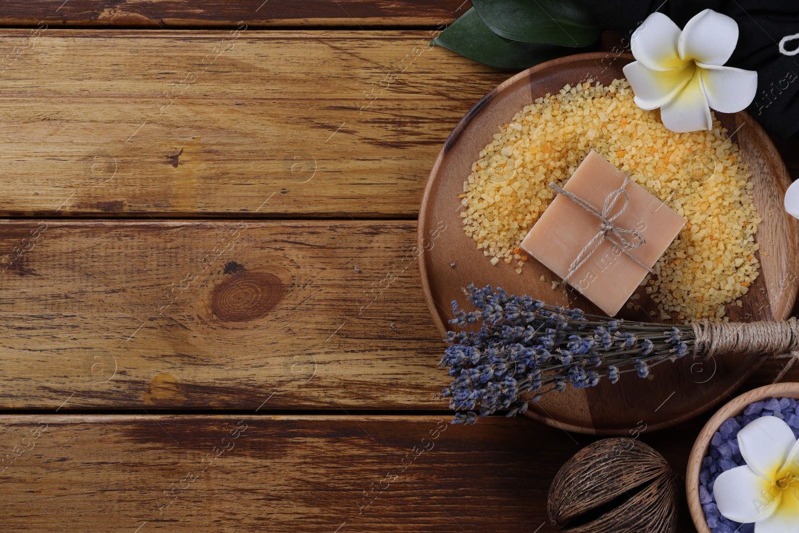 Photo of Spa composition. Sea salt, soap bar and flowers on wooden table, flat lay. Space for text