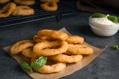 Photo of Fried onion rings served on grey table