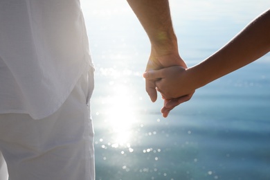 Couple holding hands together near river, closeup. Nature healing power