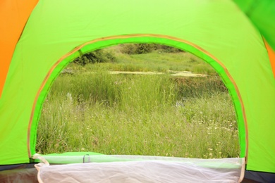 Green grass and picturesque pond, view from camping tent