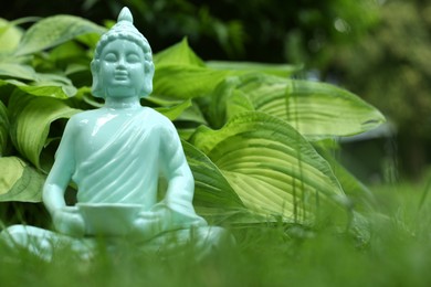 Photo of Decorative Buddha statue on green grass outdoors, closeup. Space for text