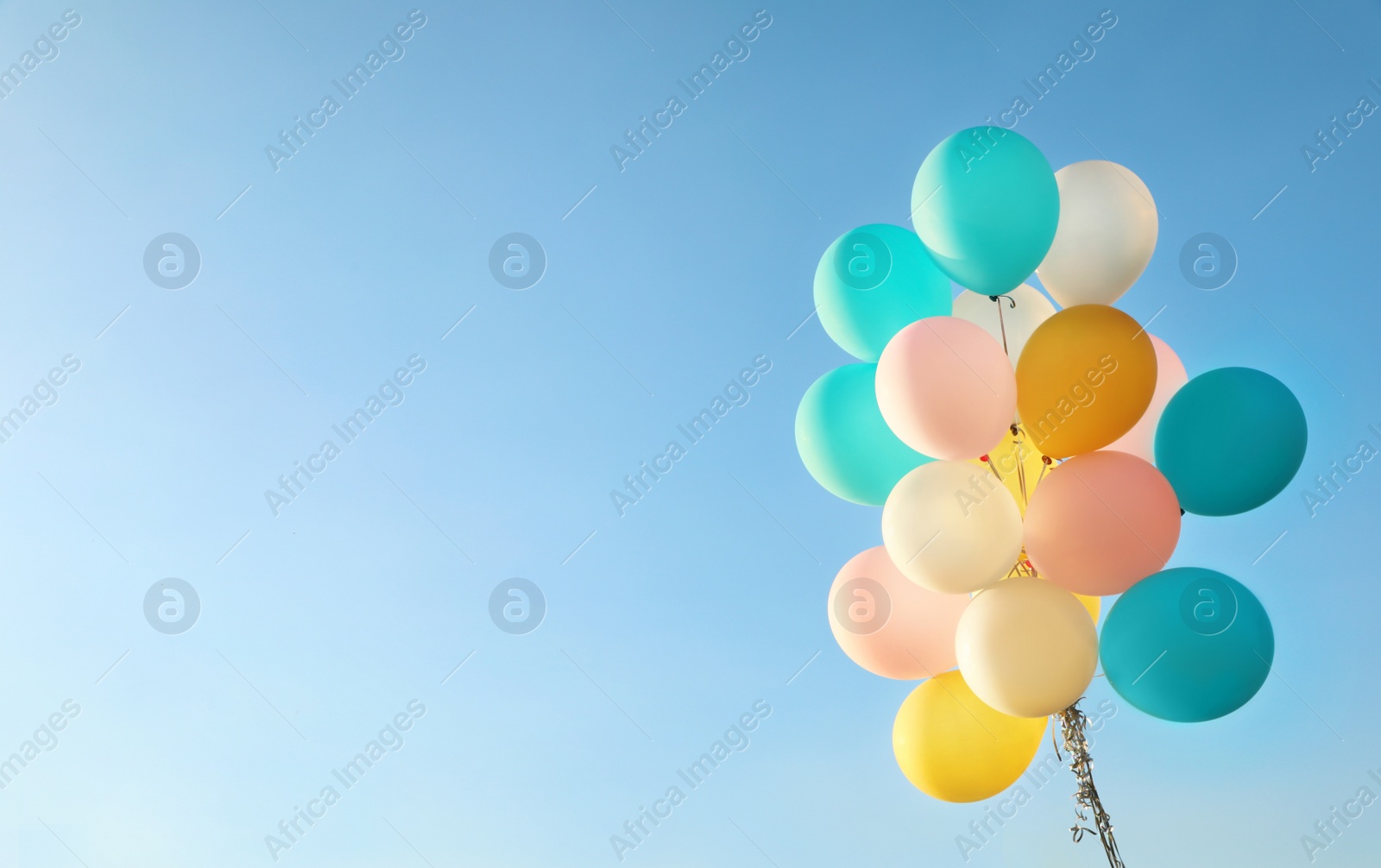 Photo of Bunch of colorful balloons against clear blue sky. Space for text