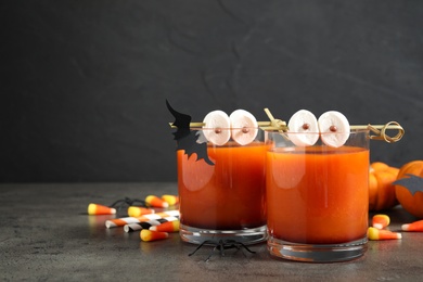 Decorated glasses with drinks on grey table, space for text. Halloween celebration