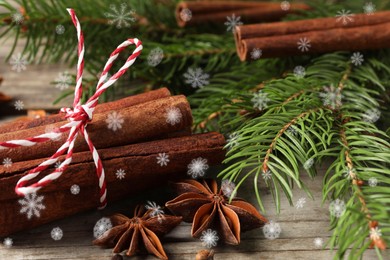 Different spices and fir tree branches on wooden table, closeup. Cinnamon, anise, cloves