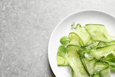 Photo of Plate with delicious cucumber salad on grey background, top view. Space for text