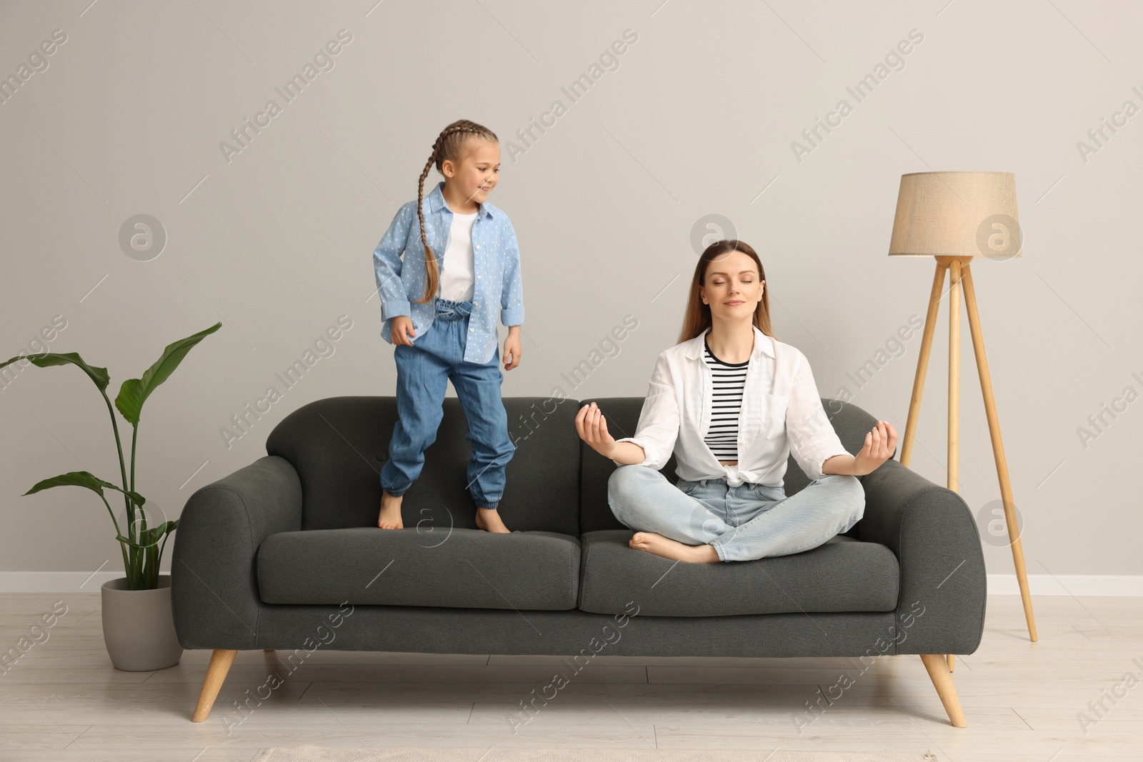 Photo of Mother meditating while daughter distracting her at home