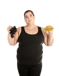 Overweight woman with hamburger and grapes on white background