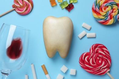 Tooth model, unhealthy food and cigarettes on light blue background, flat lay