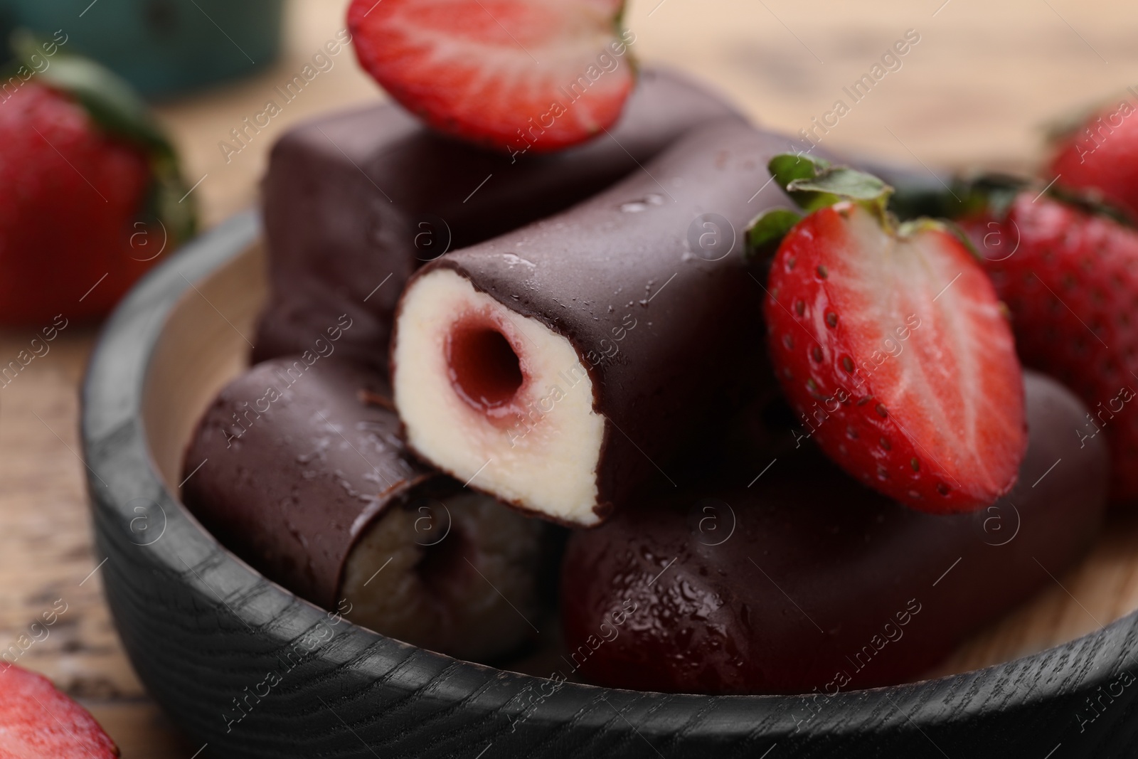 Photo of Delicious glazed curd snacks with fresh strawberries and mint on wooden table, closeup