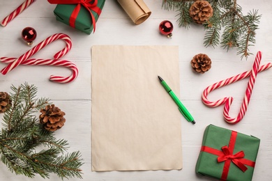 Flat lay composition with paper and Christmas decor on white wooden table. Writing letter to Santa Claus