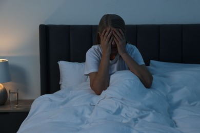 Woman suffering from headache in bed at night