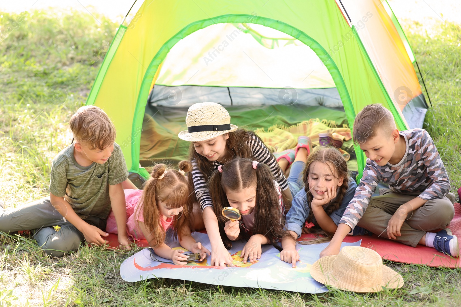 Photo of Little children with map near tent outdoors. Summer camp