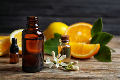 Photo of Bottles of citrus essential oil on wooden table. Space for text