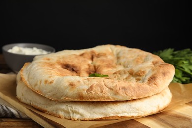 Photo of Loaves of delicious homemade pita bread on wooden table, closeup