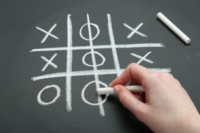 Photo of Woman playing tic tac toe on chalkboard, closeup