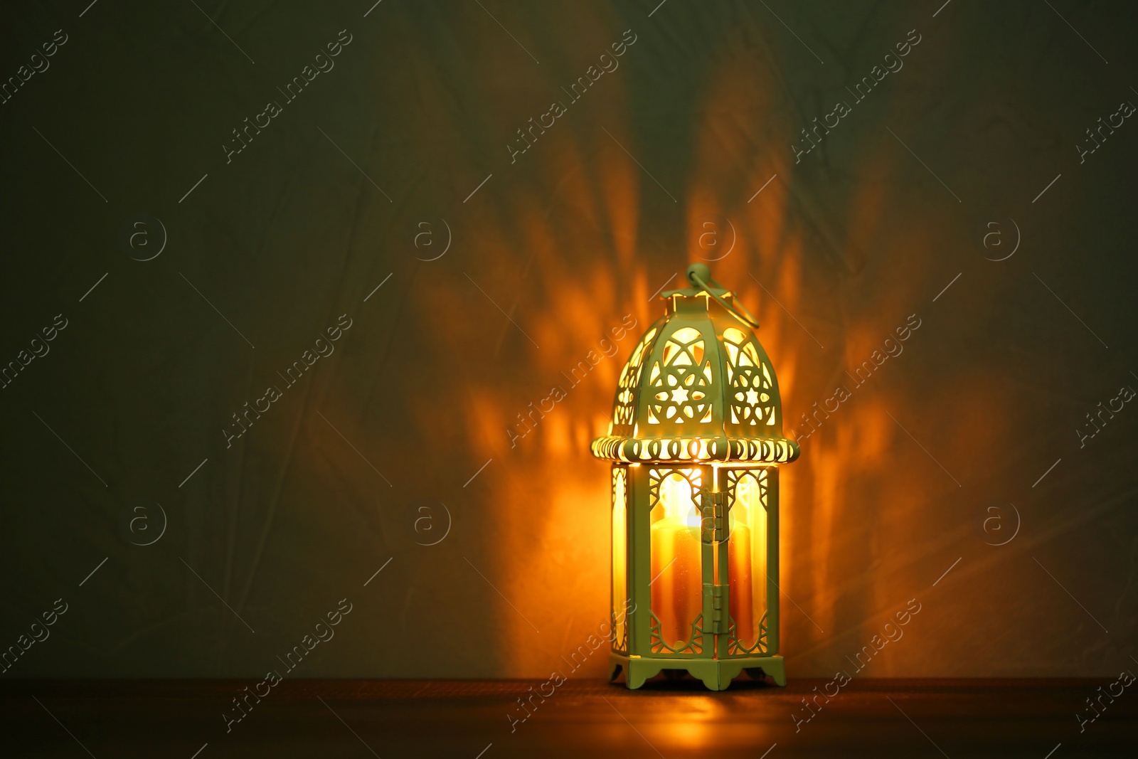 Photo of Decorative Arabic lantern on table against dark background. Space for text