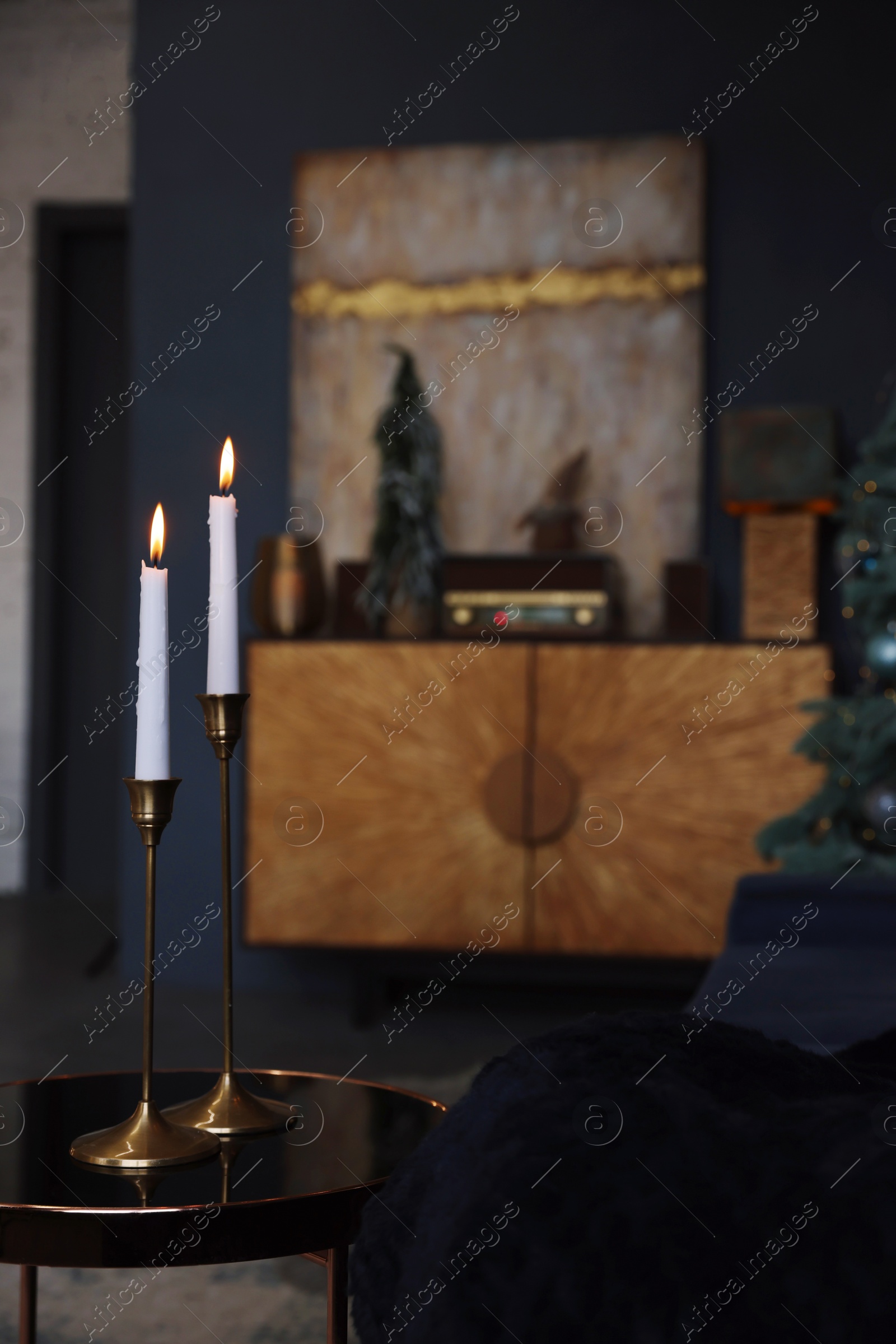 Photo of Pair of beautiful candlesticks on glass table and Christmas decor in room, space for text