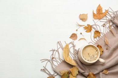 Photo of Flat lay composition with cup of hot drink and autumn leaves on white wooden table, space for text. Cozy atmosphere