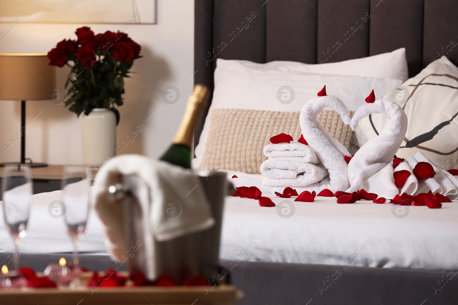 Photo of Honeymoon. Swans made with towels and beautiful rose petals on bed