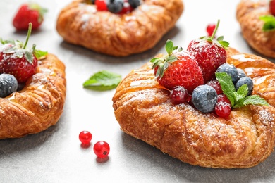 Fresh delicious puff pastry with sweet berries on light background, closeup