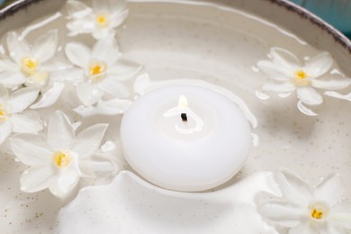 Photo of Spa composition with burning candle and beautiful flowers in water, closeup